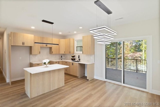 kitchen with sink, light brown cabinets, a center island, light hardwood / wood-style floors, and hanging light fixtures