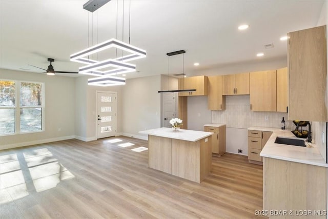 kitchen with ceiling fan, tasteful backsplash, decorative light fixtures, light brown cabinetry, and a kitchen island