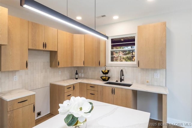 kitchen with sink, backsplash, and light brown cabinets