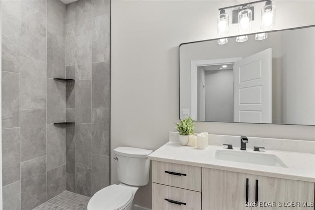 bathroom with vanity, toilet, and tiled shower