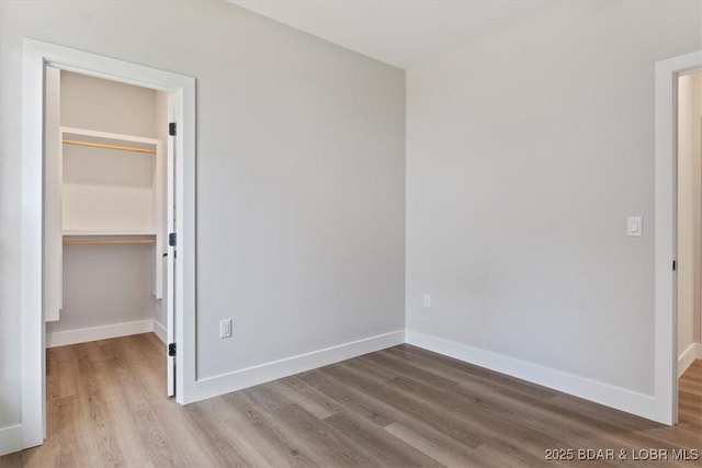 unfurnished bedroom with a spacious closet, a closet, and light wood-type flooring