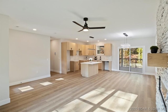 unfurnished living room featuring ceiling fan, a stone fireplace, and light hardwood / wood-style floors