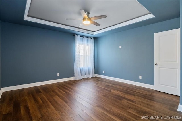 unfurnished room with ceiling fan, dark hardwood / wood-style flooring, and a tray ceiling