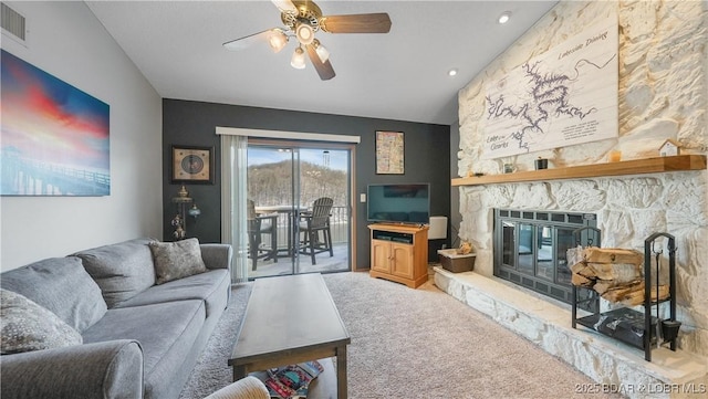 living room with vaulted ceiling, carpet, a stone fireplace, and ceiling fan