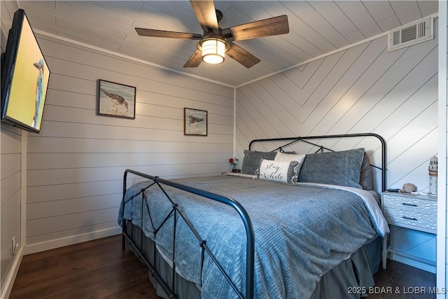 bedroom with dark hardwood / wood-style flooring, ceiling fan, ornamental molding, and wood walls