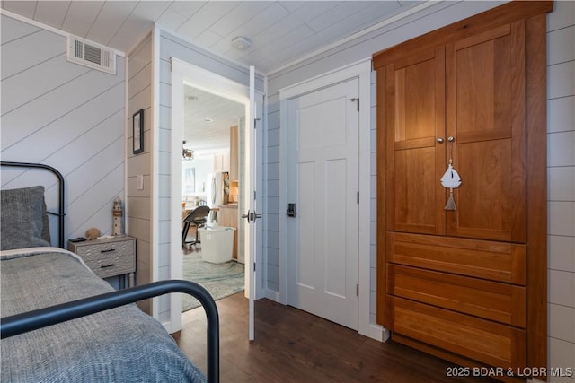 bedroom with dark hardwood / wood-style floors and wood walls