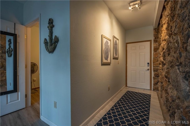 hall featuring rail lighting and light hardwood / wood-style flooring