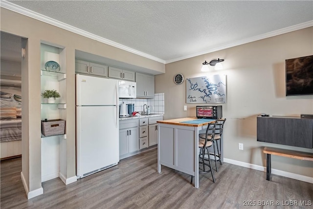 kitchen featuring wood counters, tasteful backsplash, a kitchen breakfast bar, a textured ceiling, and white appliances