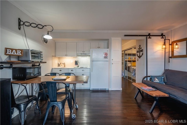 kitchen featuring a barn door, white fridge, white cabinetry, and ornamental molding