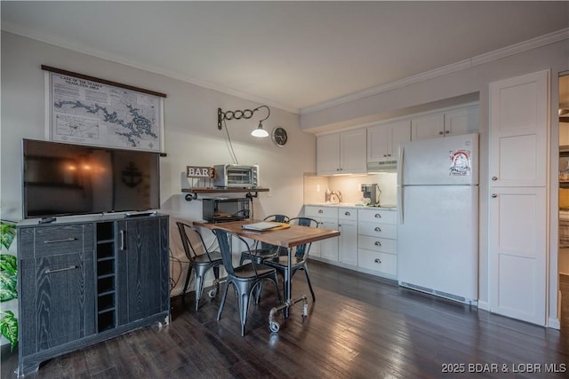 kitchen featuring dark hardwood / wood-style flooring, white refrigerator, white cabinetry, and crown molding