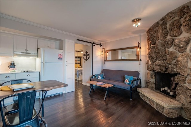 living room with a stone fireplace, dark wood-type flooring, and ornamental molding