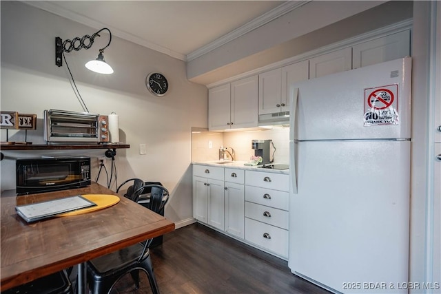 kitchen with tasteful backsplash, crown molding, white refrigerator, white cabinets, and dark hardwood / wood-style floors