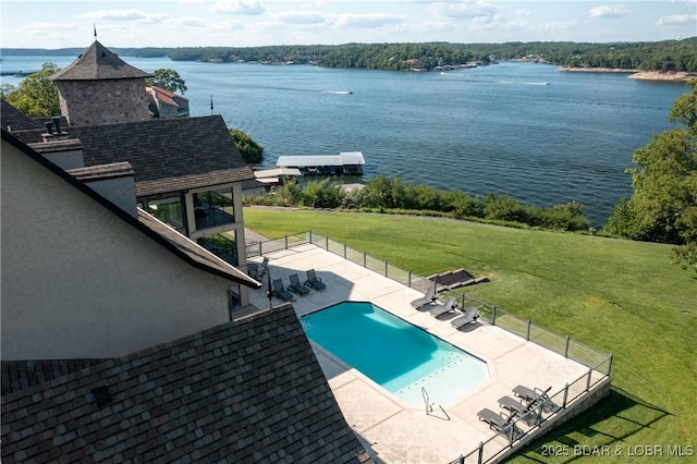 view of swimming pool featuring a lawn, a patio area, and a water view