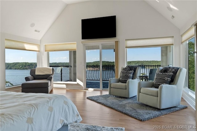 bedroom with wood-type flooring, access to outside, and high vaulted ceiling