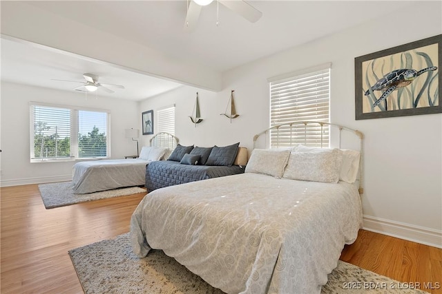 bedroom with hardwood / wood-style floors, ceiling fan, and beamed ceiling