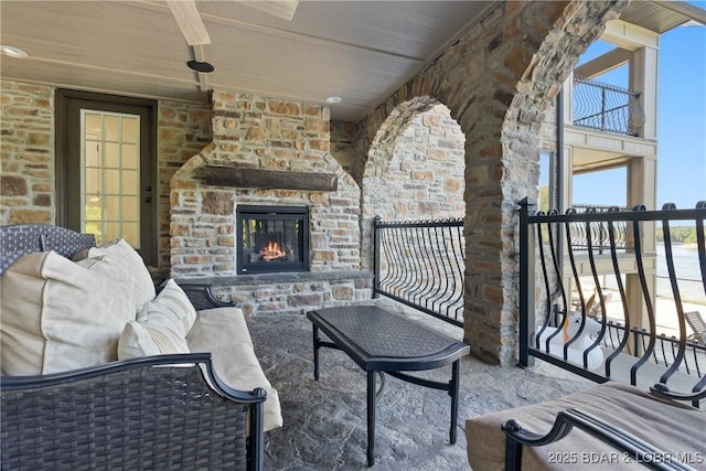 view of patio / terrace featuring an outdoor stone fireplace and a balcony