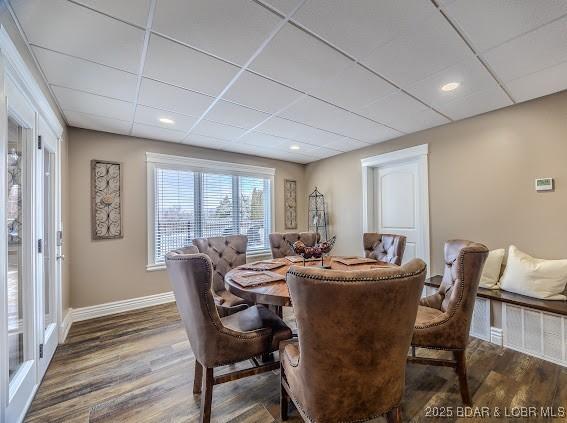 dining area with a paneled ceiling and dark wood-type flooring