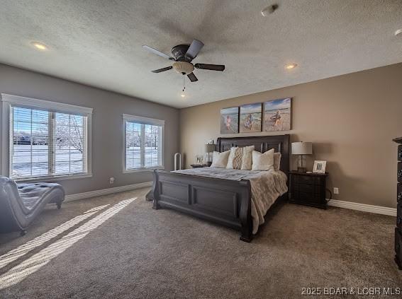 carpeted bedroom featuring ceiling fan and a textured ceiling