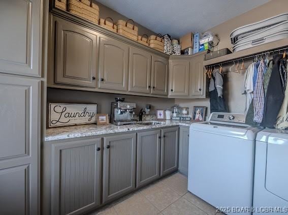 laundry area with washer and dryer, light tile patterned flooring, cabinets, and sink