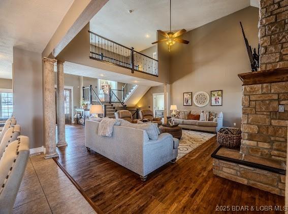 living room with a high ceiling, decorative columns, ceiling fan, and dark hardwood / wood-style floors