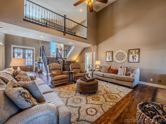 living room with ceiling fan, a high ceiling, and hardwood / wood-style flooring