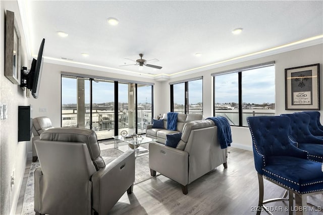 living room featuring hardwood / wood-style flooring, ceiling fan, and ornamental molding