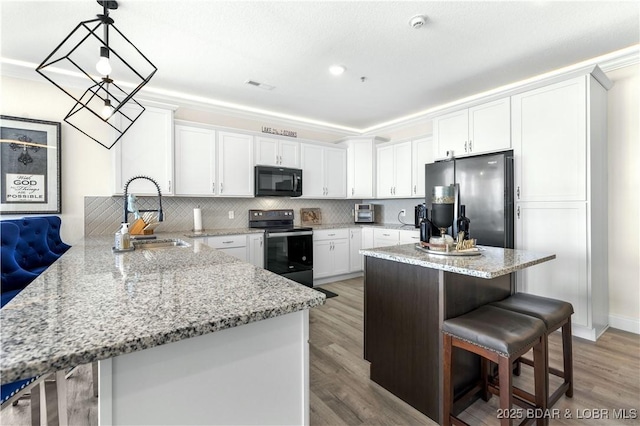 kitchen featuring sink, a center island, hanging light fixtures, a kitchen breakfast bar, and black appliances