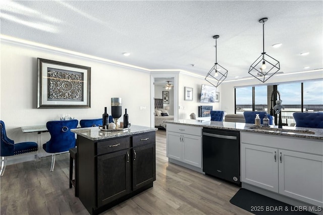 kitchen featuring light stone countertops, sink, pendant lighting, dishwasher, and white cabinetry