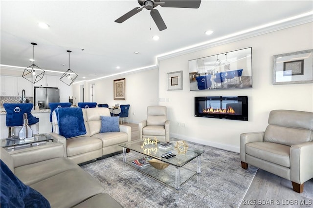 living room featuring ceiling fan, light hardwood / wood-style floors, and ornamental molding