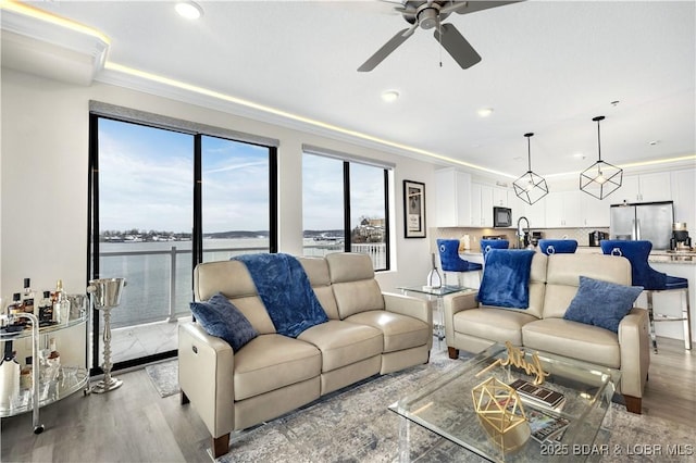 living room with ceiling fan, a water view, a healthy amount of sunlight, and light wood-type flooring