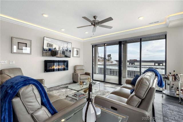 living room featuring a tray ceiling, ceiling fan, crown molding, and hardwood / wood-style flooring