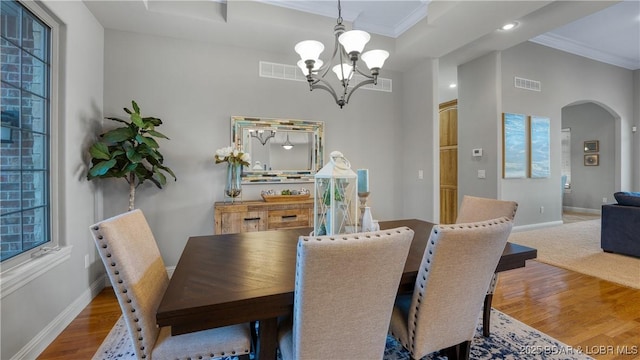 dining space with a healthy amount of sunlight, wood-type flooring, crown molding, and a chandelier