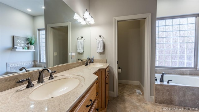 bathroom with a wealth of natural light, vanity, and a relaxing tiled tub