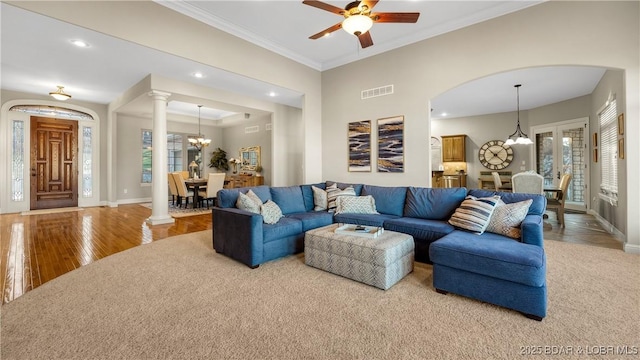 living room featuring wood-type flooring, ceiling fan with notable chandelier, and ornamental molding