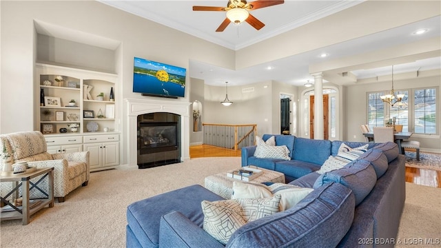 carpeted living room featuring ceiling fan with notable chandelier and ornamental molding