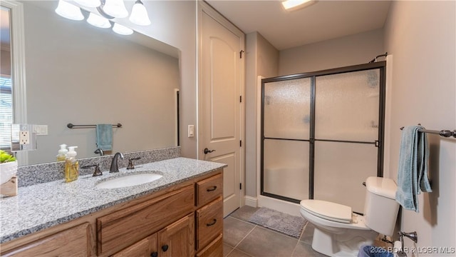 bathroom with tile patterned floors, a shower with door, vanity, and toilet