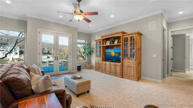 carpeted living room featuring crown molding, french doors, and ceiling fan