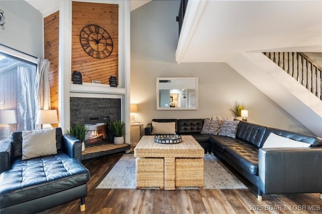 living room with dark wood-type flooring, a fireplace, and high vaulted ceiling