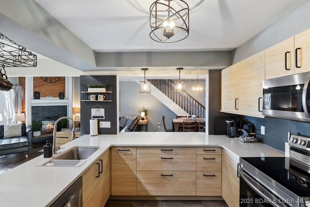 kitchen featuring appliances with stainless steel finishes, light brown cabinetry, and hanging light fixtures