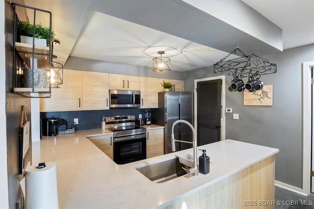 kitchen with sink, hanging light fixtures, kitchen peninsula, stainless steel appliances, and light brown cabinets