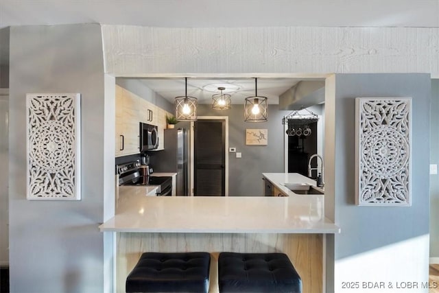 kitchen featuring hanging light fixtures, appliances with stainless steel finishes, sink, and kitchen peninsula