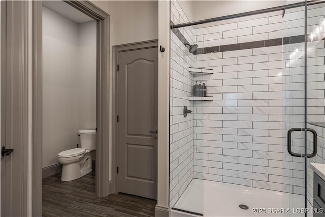 bathroom with hardwood / wood-style floors, vanity, toilet, and a shower with shower door