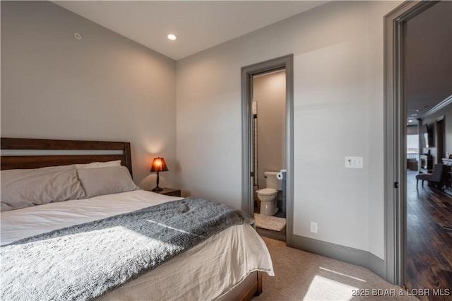 bedroom featuring dark carpet and ensuite bath