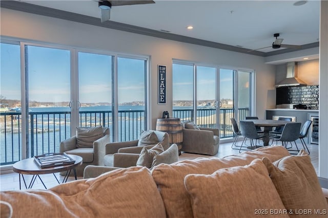 living room with ceiling fan, a water view, ornamental molding, and beverage cooler