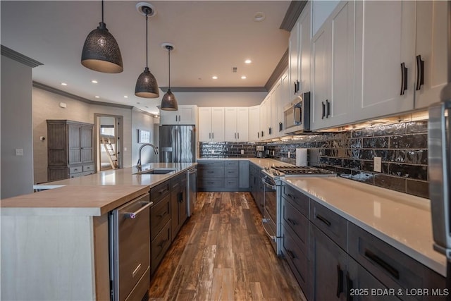 kitchen featuring stainless steel appliances, dark wood-type flooring, a large island with sink, pendant lighting, and white cabinets