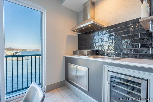 kitchen featuring decorative backsplash, wall chimney exhaust hood, beverage cooler, a water view, and light tile patterned flooring