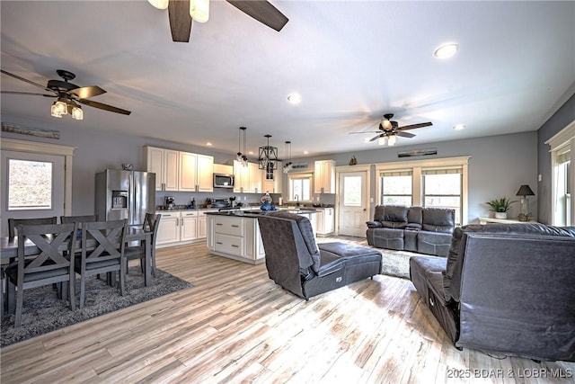 living room featuring sink, ceiling fan, and light wood-type flooring