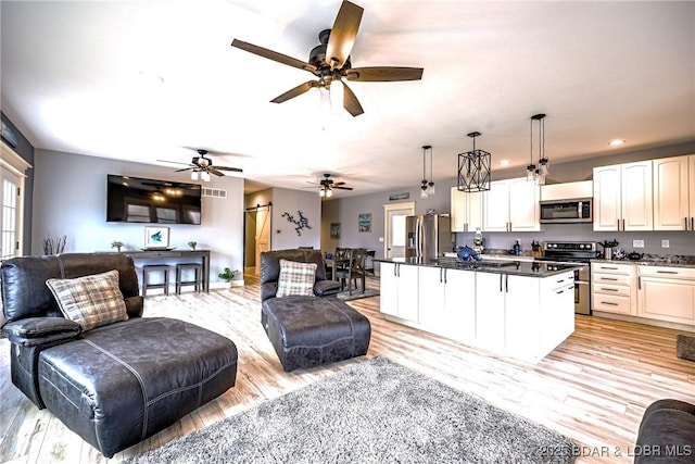 kitchen with white cabinetry, appliances with stainless steel finishes, a center island, and hanging light fixtures