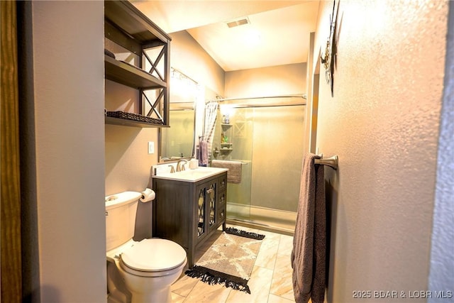 bathroom with a shower with door, vanity, and toilet