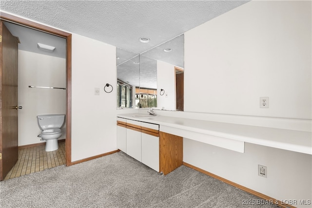 bathroom featuring a textured ceiling, vanity, and toilet